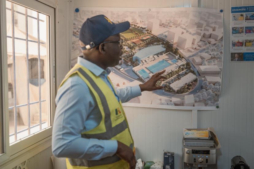 Babacar Senghor, coordonnateur du projet des Jeux Olympiques de la Jeunesse (JOJ), devant les plans de la piscine.