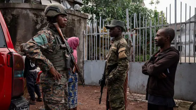 Deux militaires en uniforme discutent avec des civils dans une zone urbaine